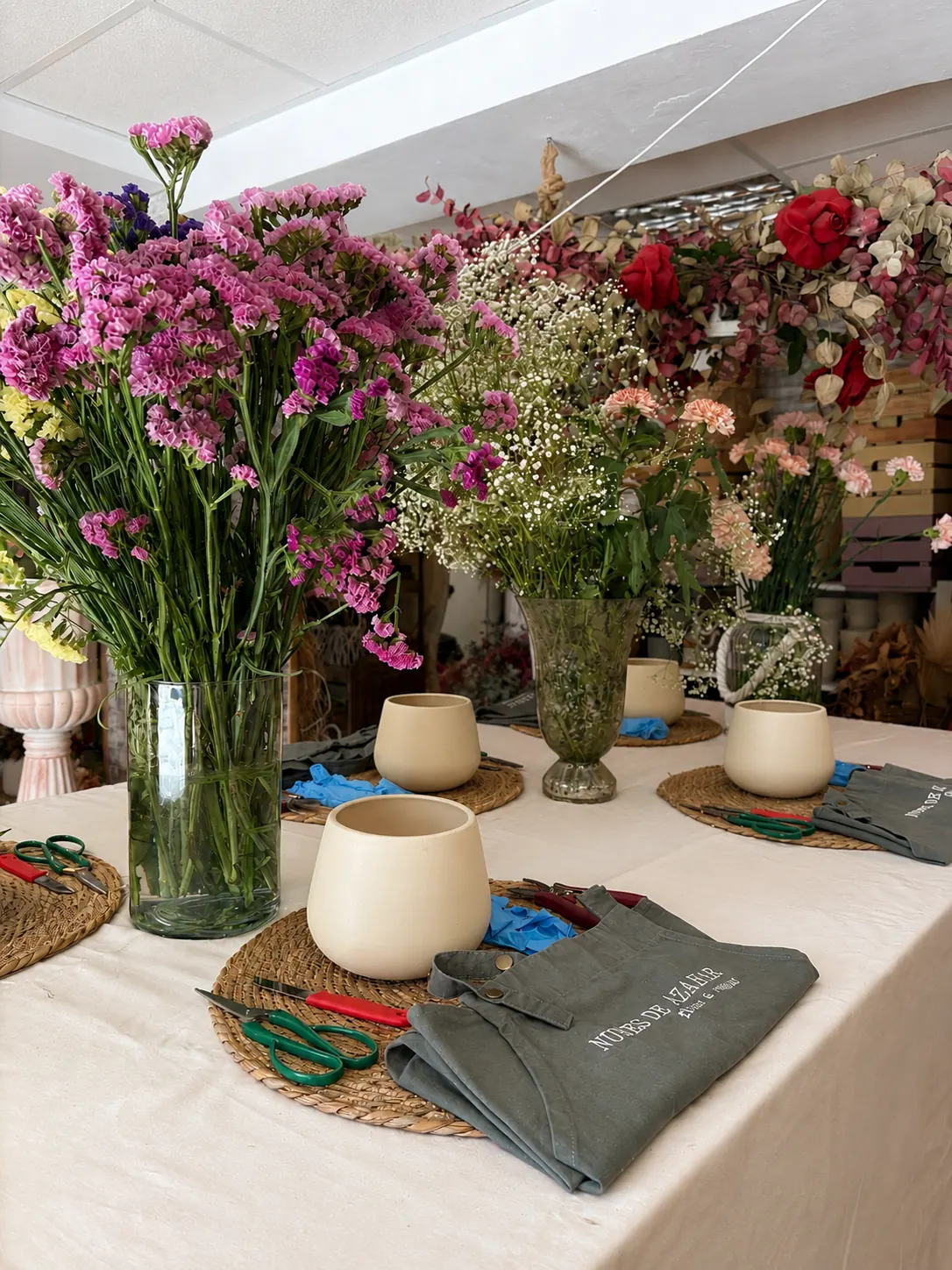Mesa del taller floral de Nubes de Azahar en Triana con delantales, tijeras y flores preparadas